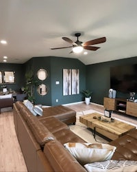 a living room with brown leather furniture and green walls